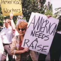 A white woman among demonstrators carries a sign reading "America Needs a Raise".