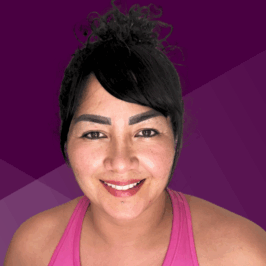 Image: A person with dark curly hair tied up in a bun, wearing a sleeveless pink top, is positioned against a purple geometric background.